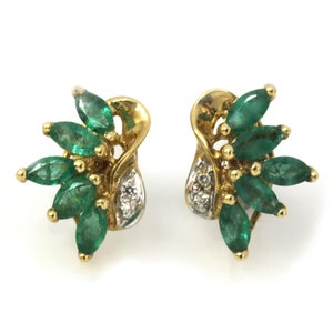Puede incluir: Un par de pendientes de oro con un racimo de piedras preciosas en forma de marquesa verde esmeralda y pequeños diamantes redondos.