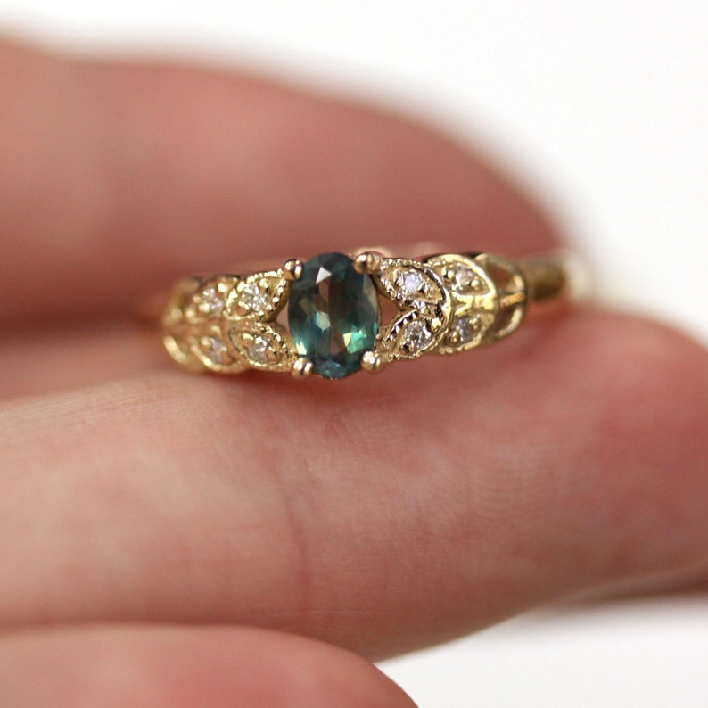 May include: A gold ring with a green gemstone and small diamonds set in a leaf design.
