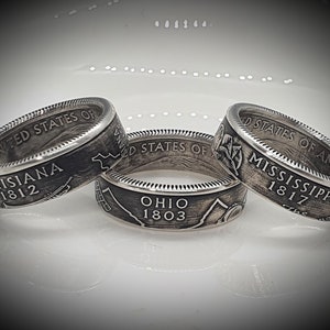 May include: Three silver rings with the words "UNITED STATES OF" and the names of states, "LOUISIANA 1812", "MISSISSIPPI 1817", and "OHIO 1803" engraved on them.