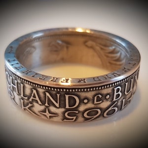 Può includere: Un anello d'argento realizzato con una moneta del 1961. L'anello presenta l'iscrizione "HIGHLAND - C. B" e una stella.