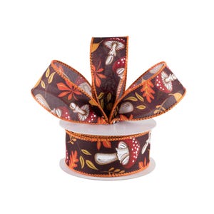 May include: A spool of brown ribbon with a white and orange mushroom print. The ribbon has a scalloped edge and is wrapped around a white spool.