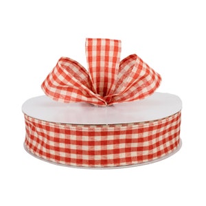 May include: A spool of red and white gingham ribbon with a bow tied on top. The ribbon is 2.5 inches wide.