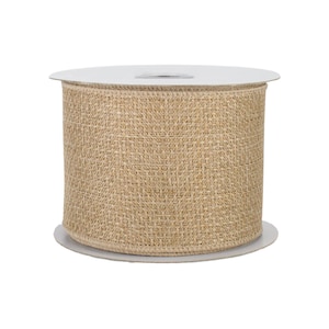 May include: A wide spool of natural tan burlap ribbon featuring a coarse, woven texture. The ribbon is wrapped tightly around a central white plastic core, displaying a consistent, neutral-colored fabric with visible cross-hatch fibers throughout.