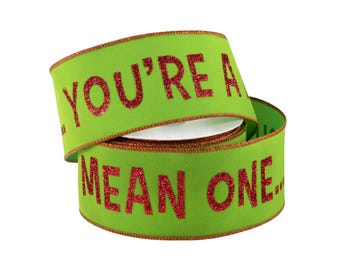 Puede incluir: Un rollo de cinta verde lima con texto rojo brillante que dice YOU'RE A MEAN ONE. La cinta cuenta con un borde de alambre y un fino acabado metálico rojo en ambos lados, creando un aspecto festivo para proyectos de manualidades y regalos.