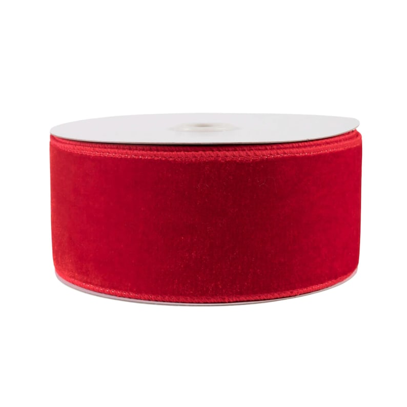 May include: A spool of red velvet ribbon. The ribbon is wound around a white cardboard spool.