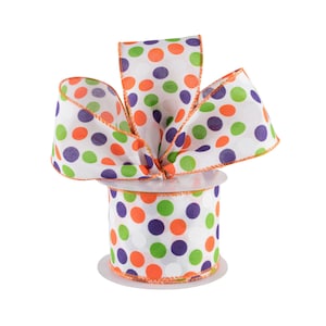 May include: A spool of white ribbon with orange, green, and purple polka dots. The ribbon is on a white spool with an orange edge.