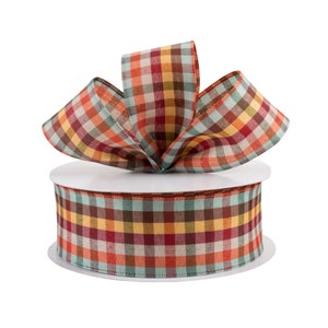 May include: A spool of plaid ribbon with a bow tied on top. The ribbon is a mix of red, orange, yellow, brown, and blue.
