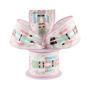 May include: A spool of white ribbon with a pink edge and a repeating pattern of nutcracker soldiers in blue, green, pink, and gold. The ribbon is on a white spool with a pink edge.