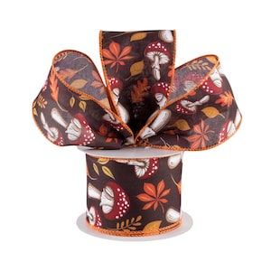 May include: A spool of brown ribbon with a white and red mushroom and orange leaf pattern. The ribbon has an orange edge.