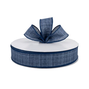May include: A spool of blue and white checkered ribbon with a navy blue edge. The ribbon is tied into a bow on top of the spool.