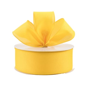 May include: A spool of bright yellow satin ribbon with a bow tied on top.