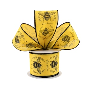 May include: A spool of yellow ribbon with a black bee and leaf design. The ribbon has a black trim and the words "bee brave" are printed on the ribbon. The ribbon is suitable for crafts, gift wrapping, and decorations.