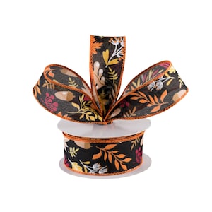 May include: A spool of black and orange ribbon with a fall leaf and acorn print. The ribbon is on a white spool and has a wired edge.