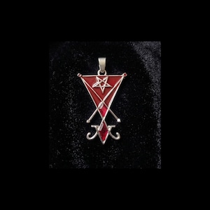 May include: Silver-toned pendant with a red enamel design. The pendant features a red triangle with a five-pointed star, a cross, and a stylized symbol at the bottom. The pendant is displayed against a dark background.
