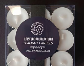 May include: A clear plastic box containing nine white tealight candles. The box is wrapped with a dark blue circular label with the text "DARK MOON MERCHANT TEALIGHT CANDLES" and a website address. The candles are arranged in a grid.