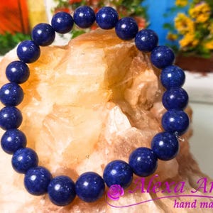 Puede incluir: Un brazalete de cuentas de lapislázuli azul oscuro. El brazalete está hecho de cuentas redondas y está enhebrado en elástico.
