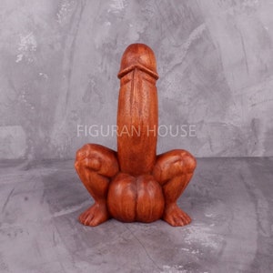 Puede incluir: Una escultura de madera de una persona sentada con las piernas cruzadas. La escultura está tallada en un estilo realista y tiene un color marrón rojizo.