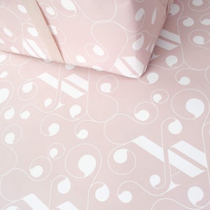 May include: Pink wrapping paper with a white geometric pattern. The pattern features swirls and circles.