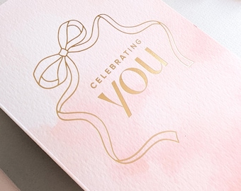 Celebrating You, Pink Birthday Card printed in gold foil with modern bow design
