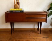 50s wooden chest of drawers with two drawers and a closet compartment.