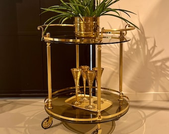 Round golden bar trolley made of brass on rubber-tired wheels.