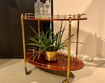 Italian bar cart with a golden brass frame on wheels.