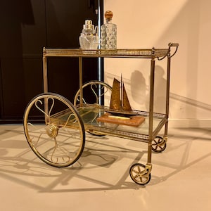 Neoklassieke barwagen met een goudkleurig messing frame op wielen.