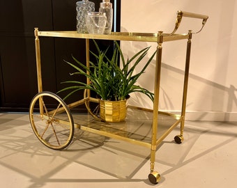 Classic bar cart with a golden brass frame on rubber-tired wheels.