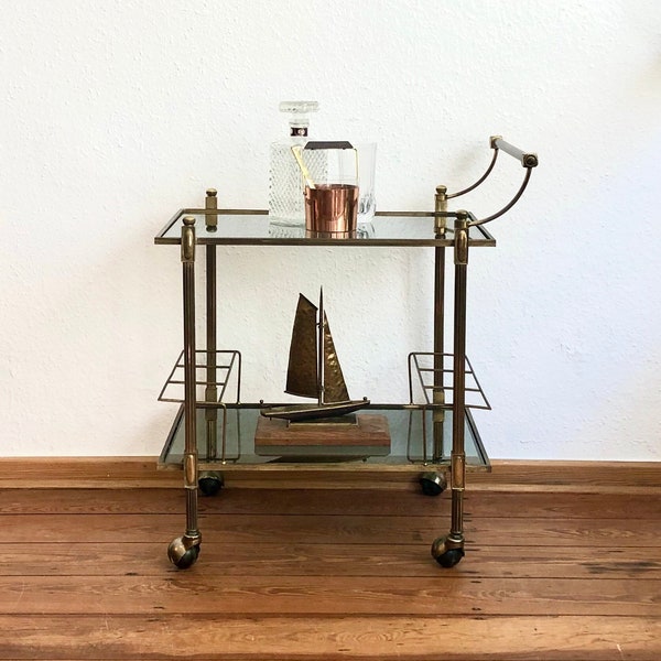 Italian bar cart with a golden brass frame on wheels.