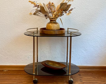 1970's golden brass bar trolley with two tinted glass tops on wheels.