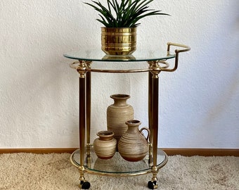 Italian bar cart with a golden frame made of brass and on wheels.