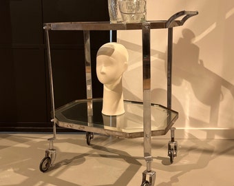 Art Deco bar cart with a silver frame on wheels.