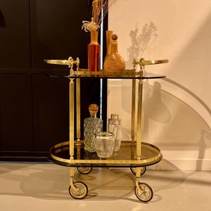 1960 年代の真鍮製の金色のバー カート。2 層の濃い色付きガラスが付いています。