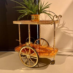 Neoklassieke barwagen met een goudkleurig messing frame op wielen.