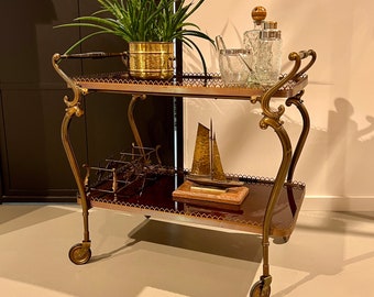 Neoclassical bar cart with a golden brass frame on wheels.