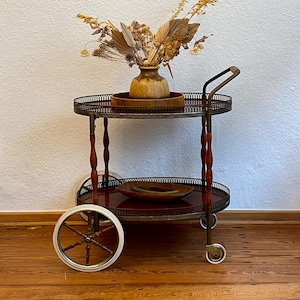 Neoclassical bar cart with a wooden frame on wheels.