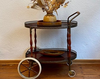 Neoclassical bar cart with a wooden frame on wheels.