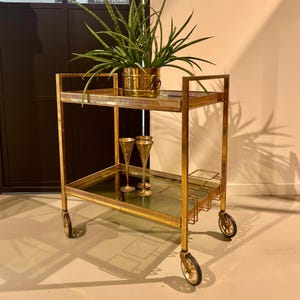 Gouden neoklassieke koperen barwagen met twee glazen niveaus op met rubber beklede wielen.