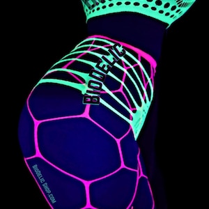May include: A neon green and hot pink fishnet bodysuit featuring a geometric hexagonal pattern that glows under ultraviolet light. The garment includes the text BIODELIC printed on the chest and hip area, with BIODELIC SHOP.COM on the leg.