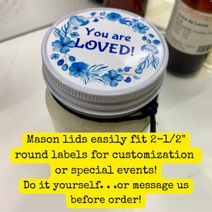 May include: A glass mason jar with a white metal lid featuring a circular sticker. The sticker has a blue floral wreath design and the text You are LOVED! in blue. A black string is tied around the neck of the jar. The lid fits 2-1/2 inch labels.
