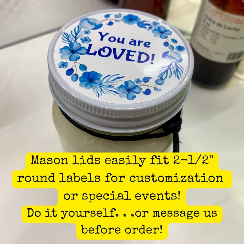 May include: A glass mason jar with a white metal lid featuring a circular sticker. The sticker has a blue floral wreath design and the text You are LOVED! in blue. A black string is tied around the neck of the jar. The lid fits 2-1/2 inch labels.