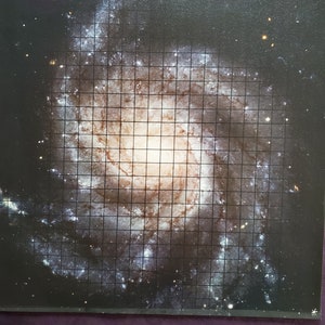 Könnte beinhalten: Ein Schwarzweißfoto einer Spiralgalaxie mit einem Gitternetz darüber. Die Galaxie ist eine wirbelnde Masse aus Sternen und Gas mit einem hellen Kern in der Mitte. Das Gitternetz ist eine Reihe von gleichmäßig verteilten Linien, die helfen, die Form und Größe der Galaxie zu zeigen.