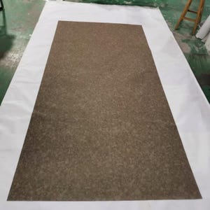 Puede incluir: Primer plano de una superficie texturizada marrón con un patrón moteado. La superficie es lisa y parece estar hecha de un material duradero.