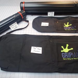 Peut inclure: Trois sacs en toile noire avec des tubes t&eacute;lescopiques rouges et noirs. Les sacs ont un logo de main verte avec le texte "The Gripmat Get a Grip on Your Game". Les tubes sont &eacute;tiquet&eacute;s &agrave; la main indiquant leur taille : "Medium Tube 18" x 24" x 1/2", "36" Inch Canvas", et "36" Tube 18" x 48" x 1/2".