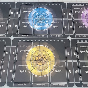 Puede incluir: Seis tableros de juego negros y blancos con un diseño de rosa en vitral de diferentes colores. Cada tablero tiene el texto "Quick Spell" y "Spell 1", "Spell 2" y "Spell 3" impreso en él.