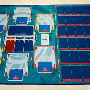 May include: A blue and green game mat with a yellow and red border. The mat has a grid of 20 spaces for cards, a section for a "bad guy" card, and a section for "villain schemes".