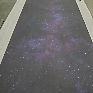 Puede incluir: Un lienzo gris oscuro con una imagen impresa de una galaxia con una nebulosa blanca, azul y rosa. La galaxia está llena de estrellas blancas.