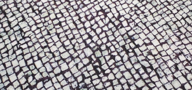 May include: A close-up of a white and black patterned fabric with a repeating pattern of small squares. The fabric has a textured surface.