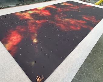 May include: A black gaming mat with a nebula design featuring red, orange, and green colors. The mat has a subtle sparkle effect and the text "GripMat" in the bottom right corner.