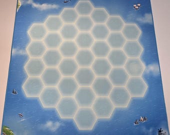 May include: A blue game mat with a sea and sky design. The mat features a central honeycomb pattern with a light blue glow. The edges depict a seascape with islands, clouds, and ships. The mat is designed for tabletop games.